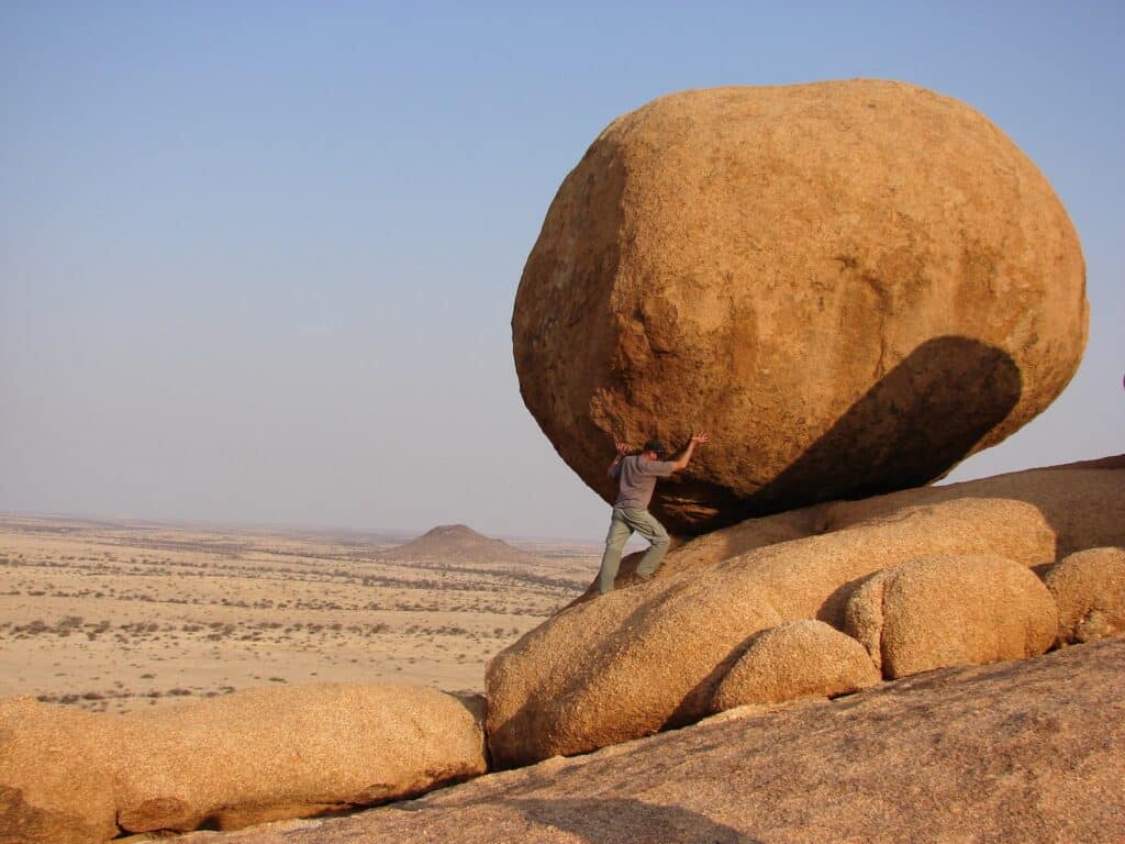 man standing beside rock formation